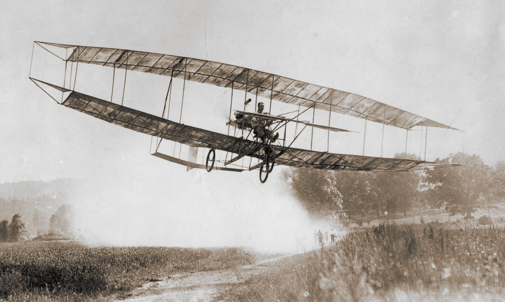 Glenn Curtiss pilots June Bug showing innovative triangular wingtip ailerons.
